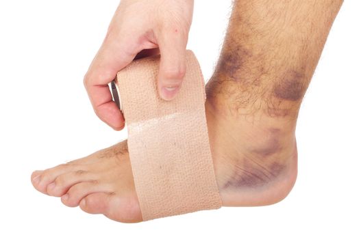 young male with sprained ankle applying medical bandage (isolated on white background)