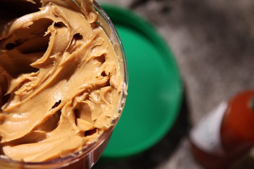 A closeup shot of a jar of peanut butter, shot in bright sunlight.