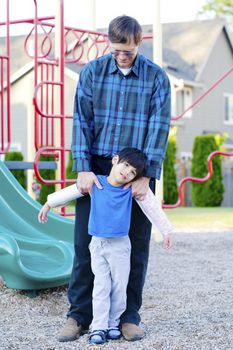 Father helping disabled son at playground