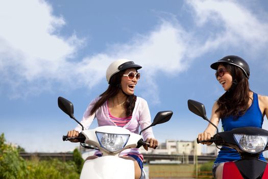 Happy girls having road trip on a scooter