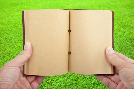 Opened book in hand  on the grass field