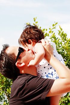 father in early thirties gives his son a kiss on the cheek in th