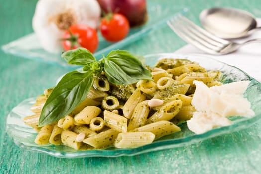 Pasta with pesto on green glass table