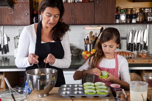 Mother and daughter filling cupcakes in kitchen