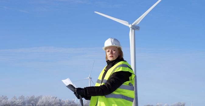 engineer or architect with white safety hat and wind turbines on background