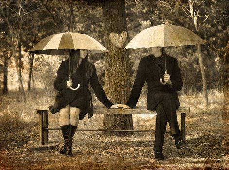 Two sitting at bench in rainy day.