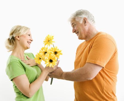 Middle-aged man giving woman bouquet of yellow flowers.