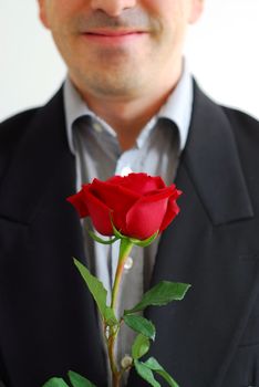 Man in black suit holding a red rose