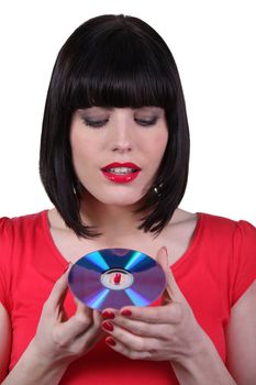 Dark -haired woman holding compact disc in hands