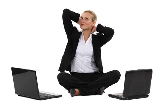 Blond businesswoman sat cross-legged with two laptops