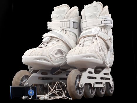 roller skates and mp3 player with headphones isolated on black background