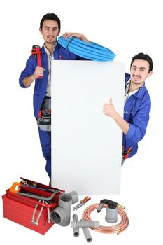 Twin tradesmen standing around a blank sign