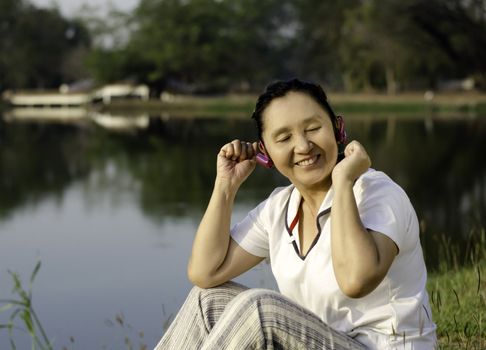 Beautiful asian woman listening music in headphones with closed 