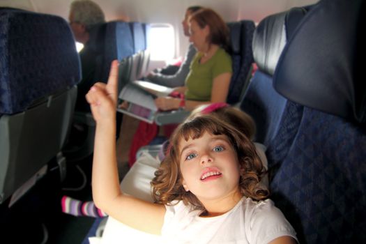 little girl inside aircraft rising up finger smiling