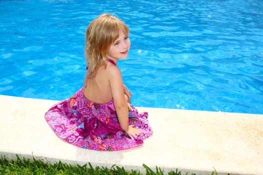 Little blond girl sitting smiling swimming pool outdoor
