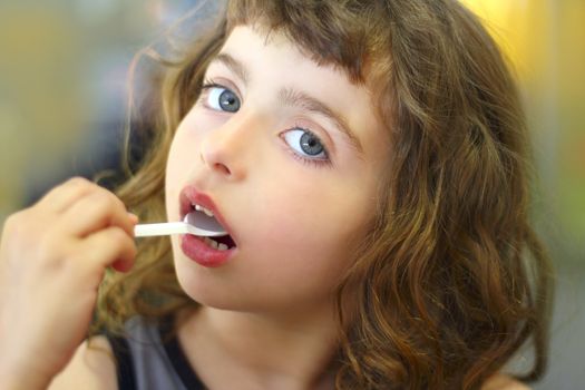 brunette little girl eating plastic spoon