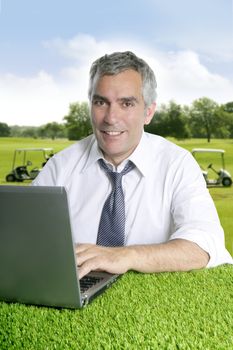 senior businessman golf course working computer green grass desk