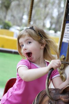 little blond girl playing horses merry go round
