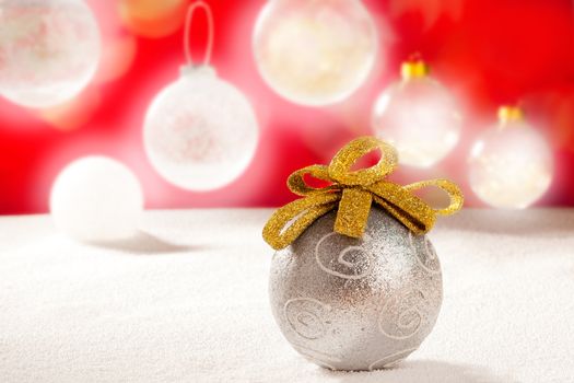 Christmas silver bauble with golden loop on snow