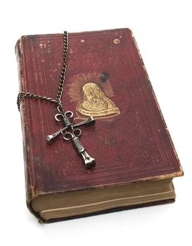 Antique red bible with unique nail cross, isolated on white background