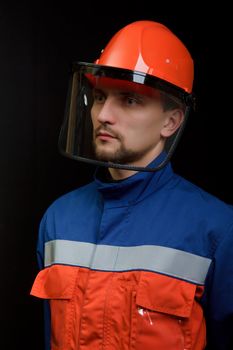 The worker in overalls and a helmet