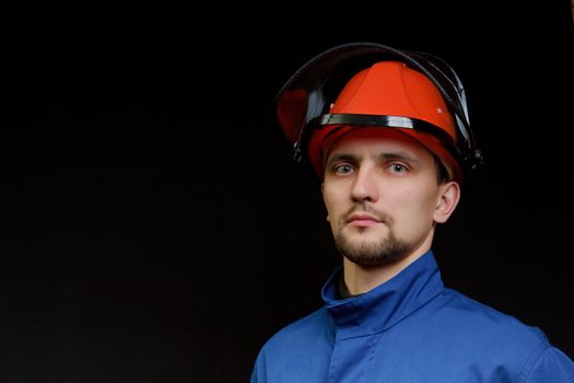 The worker in overalls and a helmet