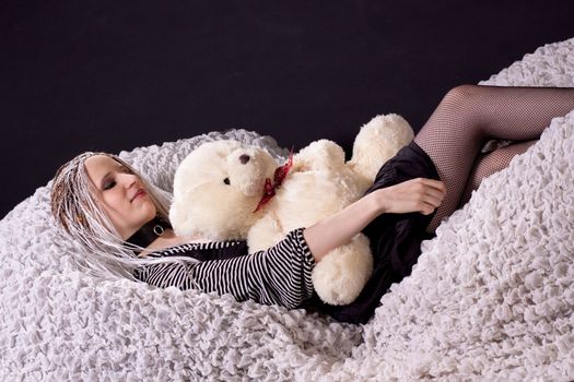 Lying girl with white hear and teddy bear
