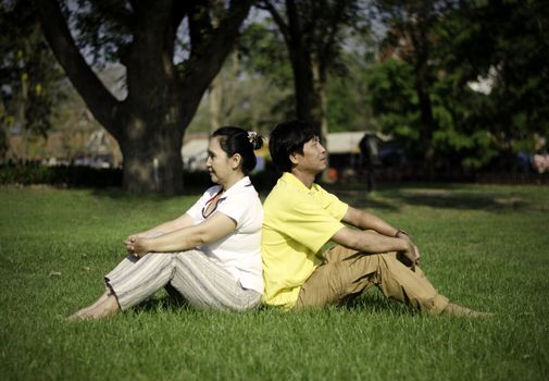 Portrait of beautiful couple sitting on ground in park