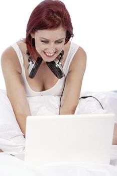 Attractive young woman listening to music at home on her bed