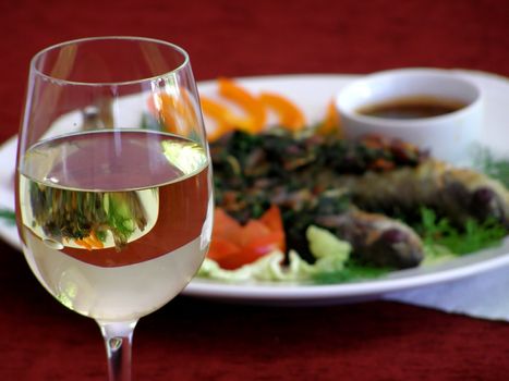 Wine-glass with a fish meal on the background