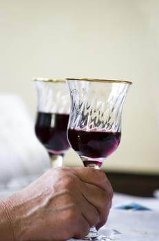 The glass of black wine hold by hand of older woman
