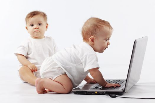 Two cute babies playing with laptop