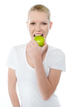 Young girl eating nutritious green apple isolated over white