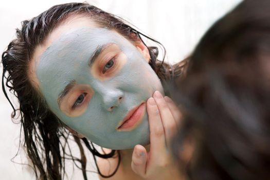 A woman putting a mud mask on her face