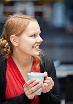Smiling young woman with cup of chocomilk