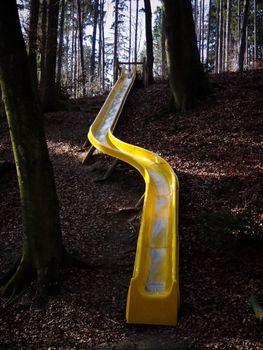 A yellow sliding board in the woods