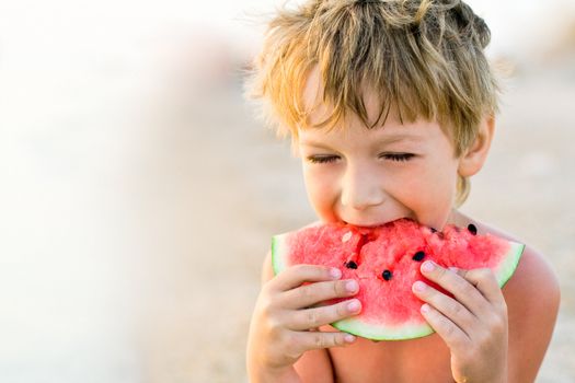 boy taking a bite of watermelon