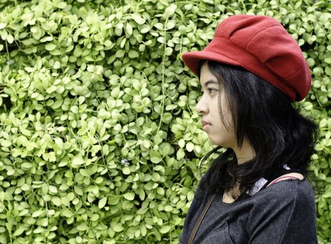 Asian girl with red hat in park on a background of green nature 