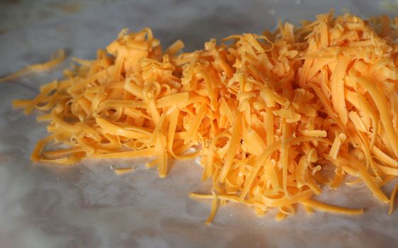 A pile freshly grated cheddar cheese.