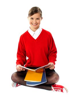 Pretty school girl seated on floor, holding book