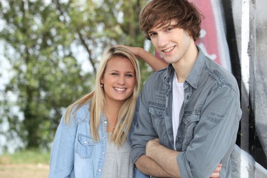 Two teenagers stood outdoors leaning against wall