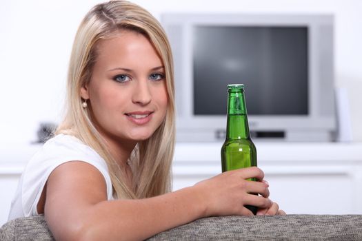 Young woman at home with a bottle of unopened lager