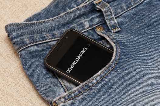 telephone with the word "downloading" in pocket of the jeans