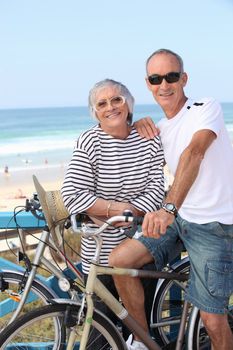 senior couple riding bikes on the beach