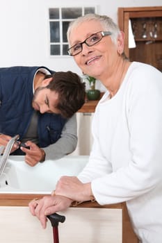 Handyman fixing a kitchen tap for a senior woman