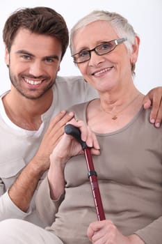 Smiling young man with his arms around a senior woman in glasses