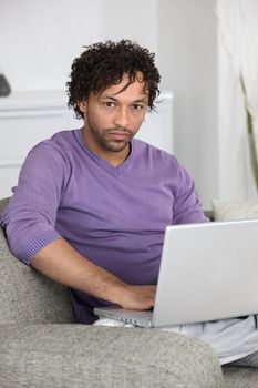 unhappy man doing computer on a couch