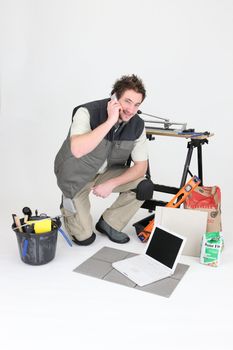 craftsman making a call near laptop and miscellaneous tools