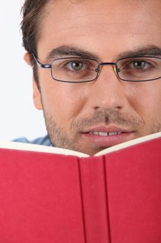 Man in glasses reading a red hardback book