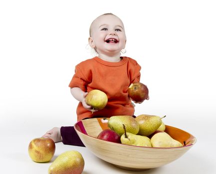 laughing baby with apples and pears laying in bowl - studio shot